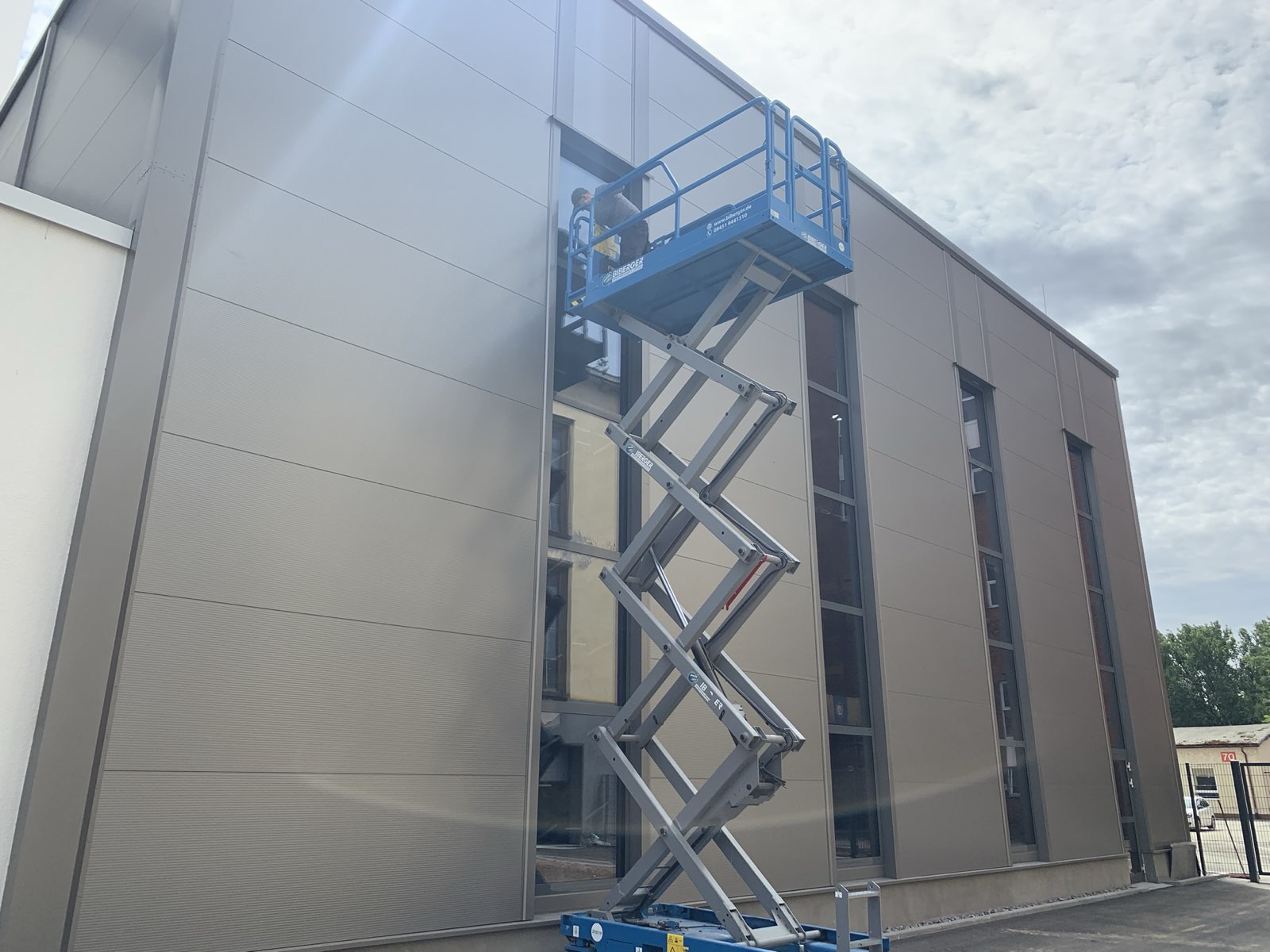 Folienmontage an einer Gewerbefassade mit Hebebühne