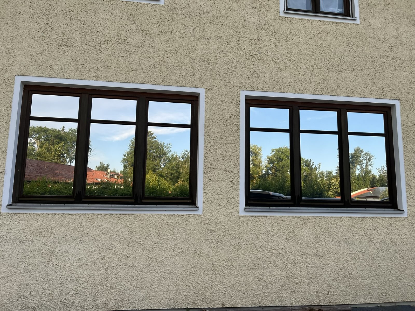 Wohnhaus mit Spiegelfolie, in den Fenstern spiegeln sich Bäume und Himmel